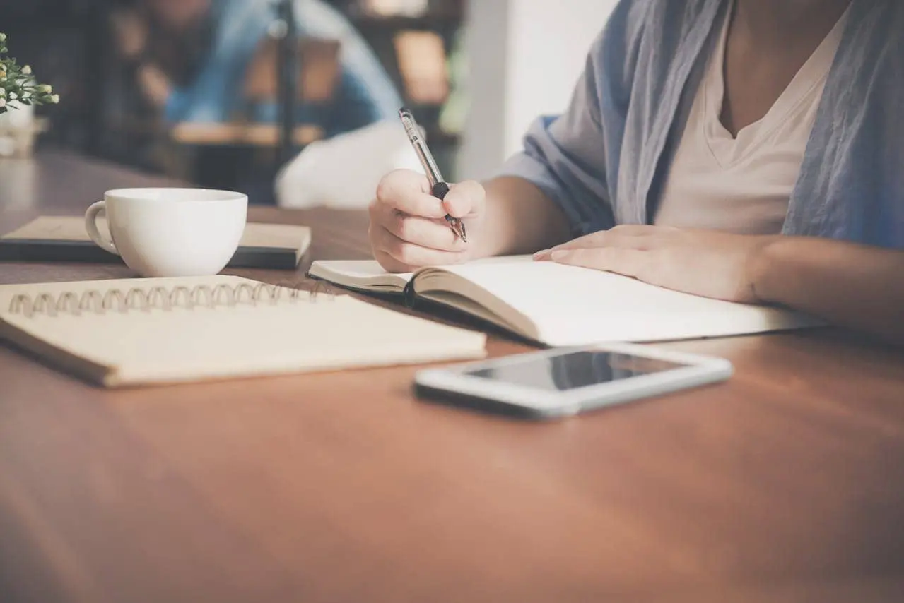 woman writing an article on a wooden desk
